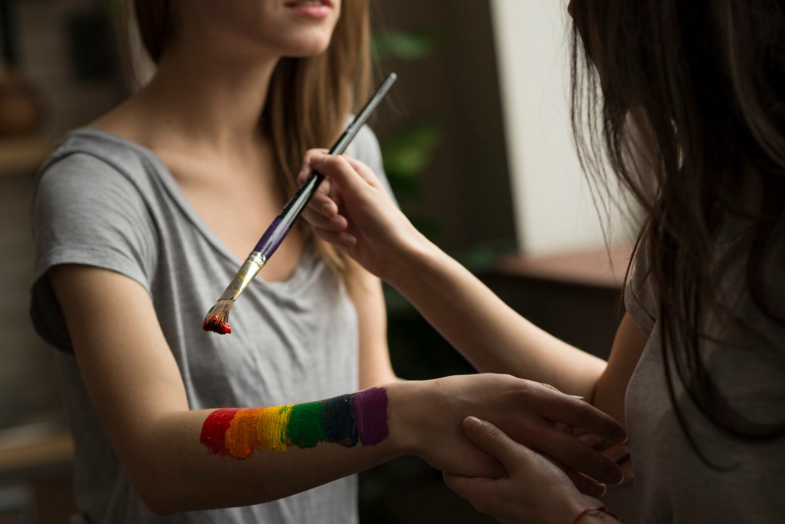 young-woman-painting-rainbow-flag-her-girlfriend-s-hand